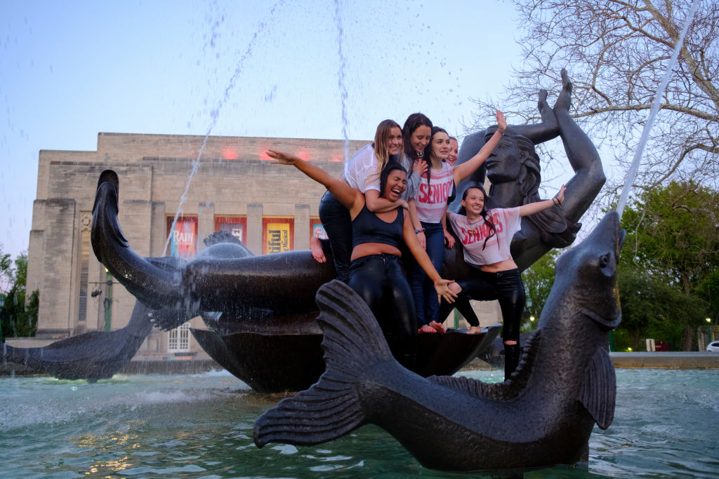 A group of Indiana University students who just finished graduating from the Kelley School of business during a video ceremony celebrate afterwards by jumping into waters of the Showalter Fountain and posing for photographs, as seen in May 2020. (Photo by Jeremy Hogan—SOPA Images/LightRocket/Getty Images)