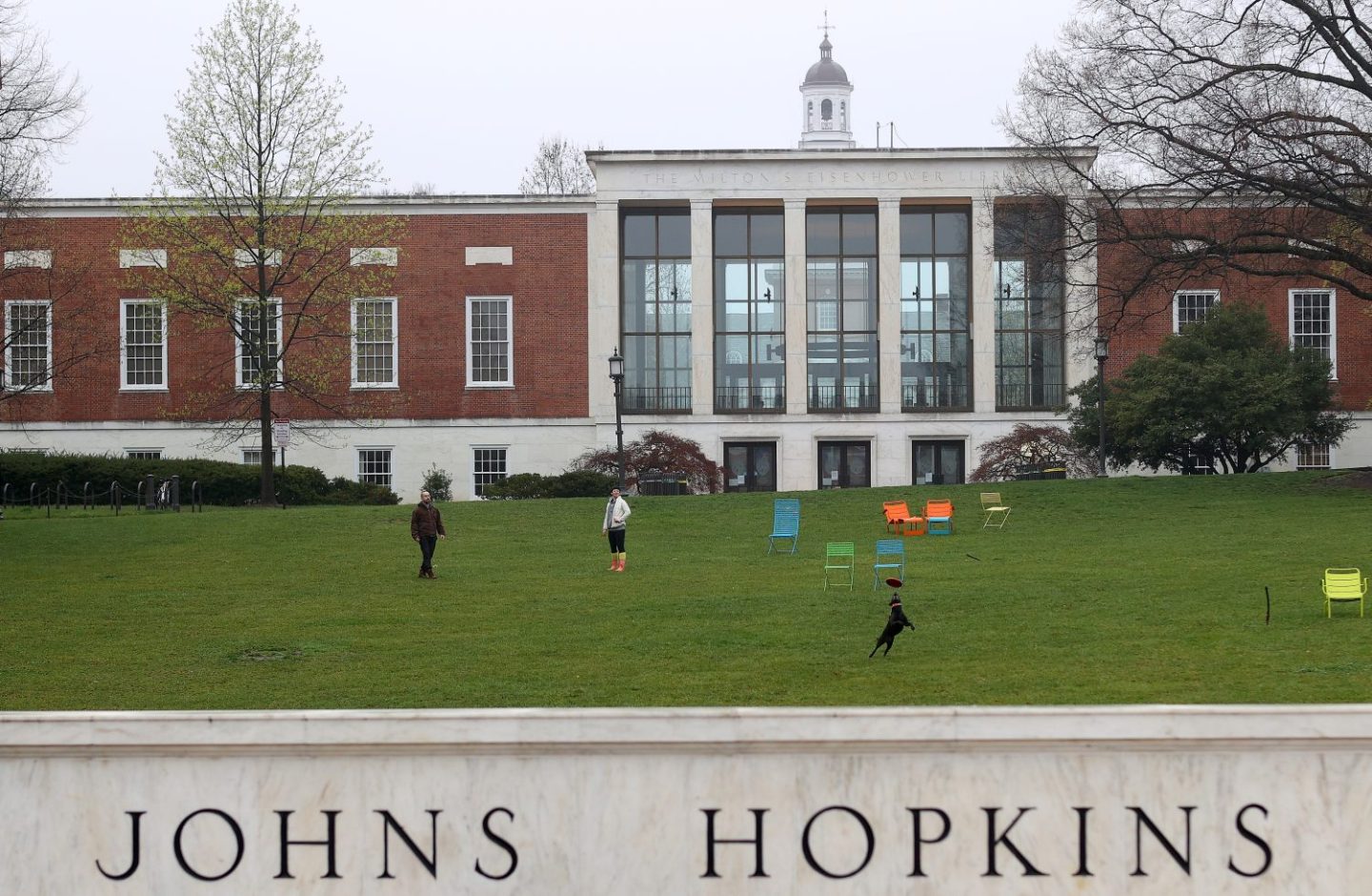 A couple throw a frisbee for a dog on the campus of The Johns Hopkins University, as seen in March 2020 in Baltimore, Maryland. (Photo by Rob Carr/Getty Images)