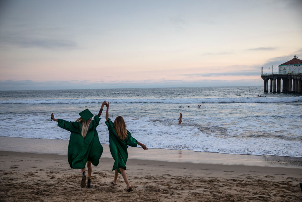 Sophia Strauss,17, left and Sarah Hoffmeister,17, right, celebrate following their drive-through graduation from Mira Costa High School in Manhattan Beach, CA, and a walk along the Strand path from Hermosa Beach Pier to the Manhattan Beach Pier, as seen in June 2020. (Jay L. Clendenin—Los Angeles Times/Getty Images)