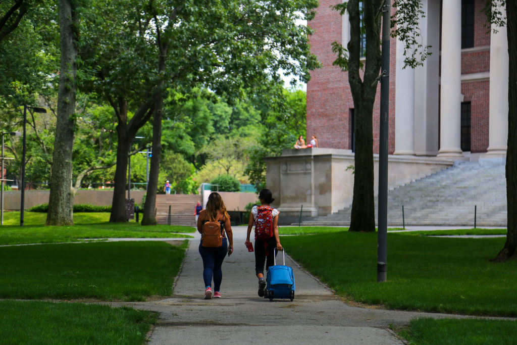 Two students are seen leaving campus with baggage at Harvard University, as seen in July 2020. (Photo by Anik Rahman—NurPhoto/Getty Images)