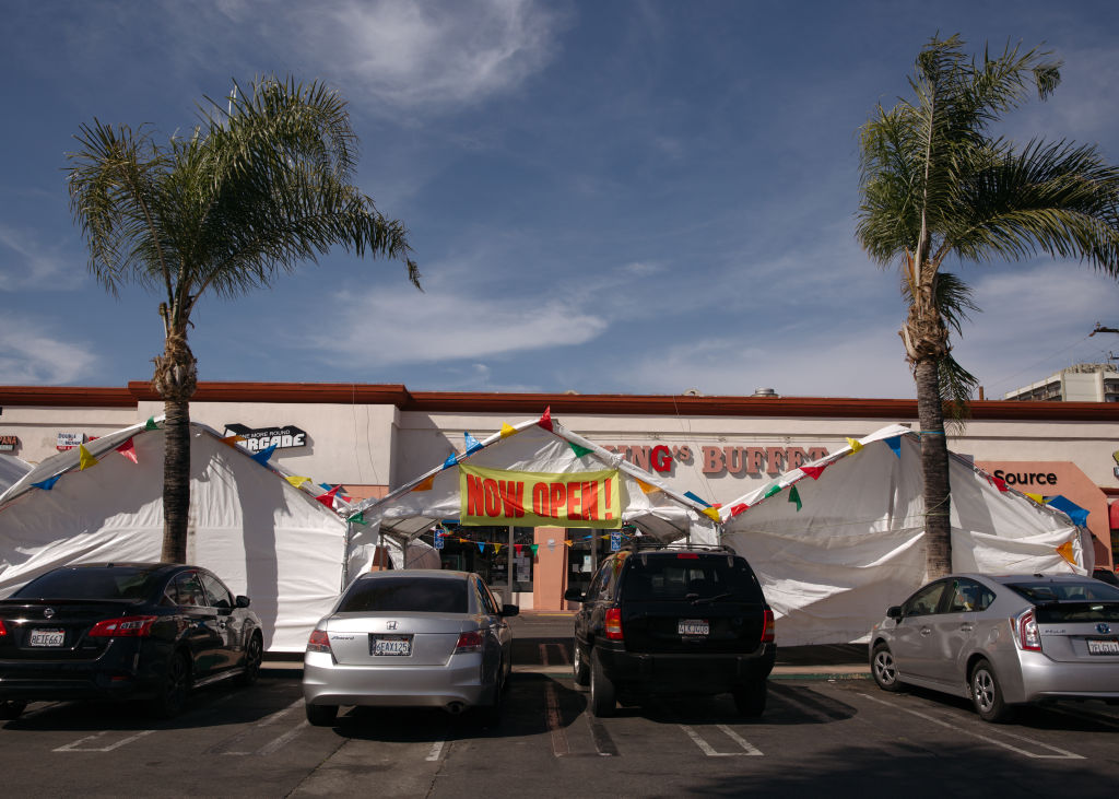 A "Now Open" sign outside a commercial tent at a parking lot in Huntington Park, California, as seen in March 2021. (Photographer: Jessica Pons—Bloomberg/Getty Images)