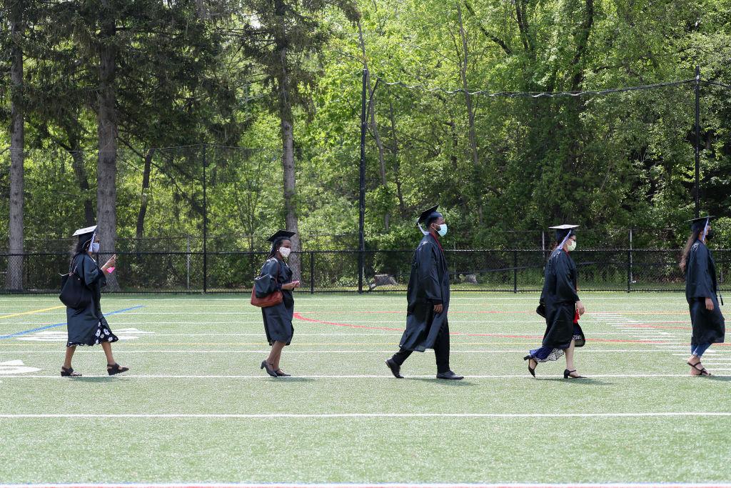 Graduates at Quincy College enter during the Quincy College graduation at Veterans Memorial Stadium, as seen in May 2021. (Photo by Suzanne Kreiter—The Boston Globe/Getty Images)