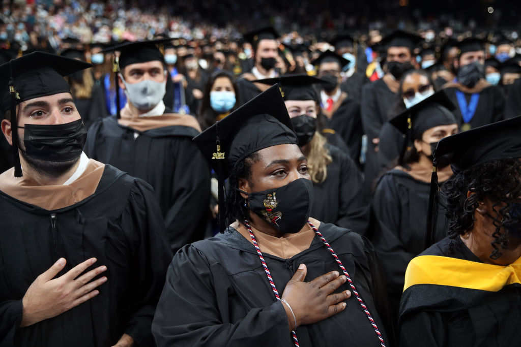 UMass graduates stand for the national anthem during the 53rd Commencements of the University of Massachusetts Boston at TD Garden in Boston, MA, as seen in August 2021. (Photo by Craig F. Walker—The Boston Globe/Getty Images)