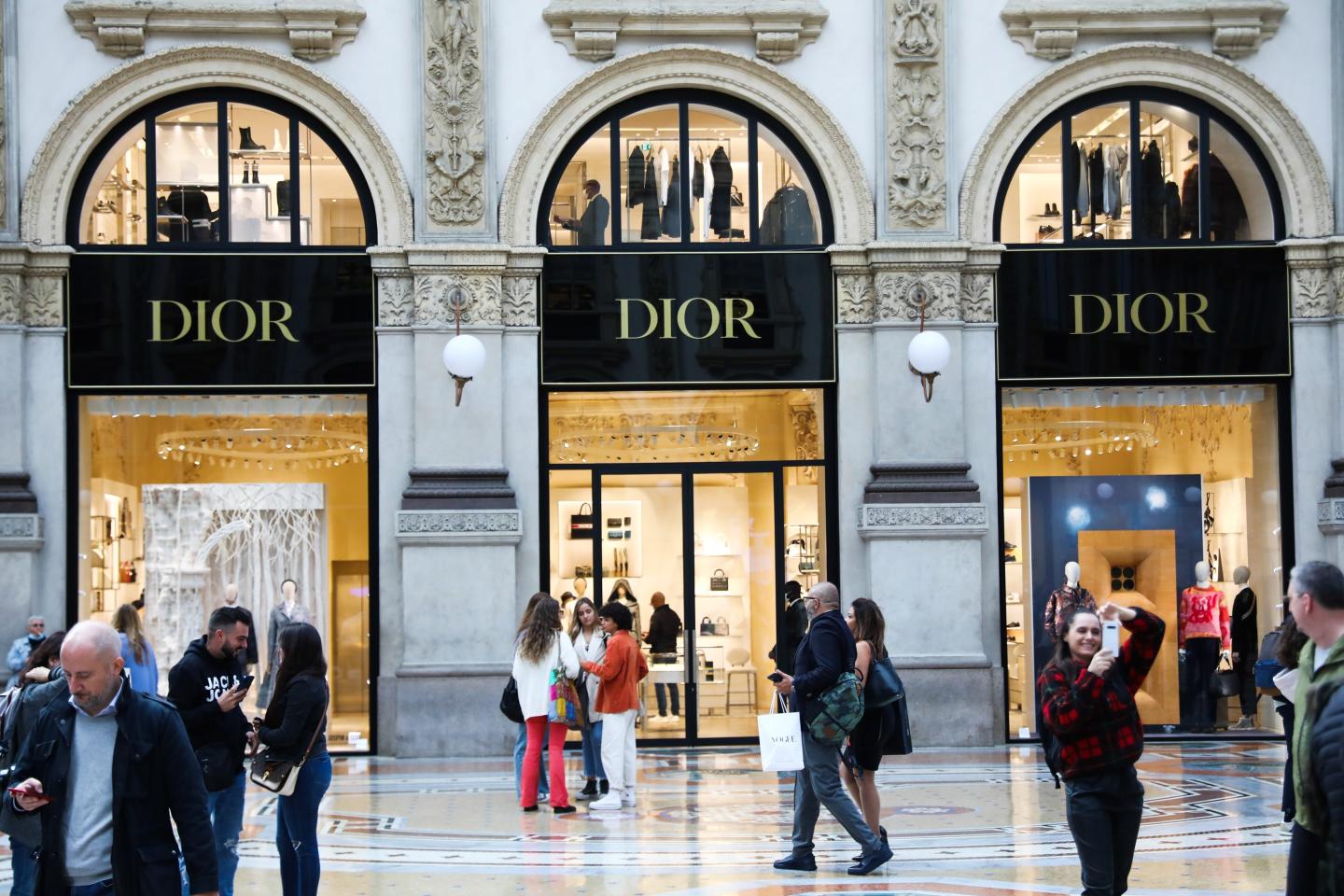 Crowds of people walking in a shopping area with a Dior store