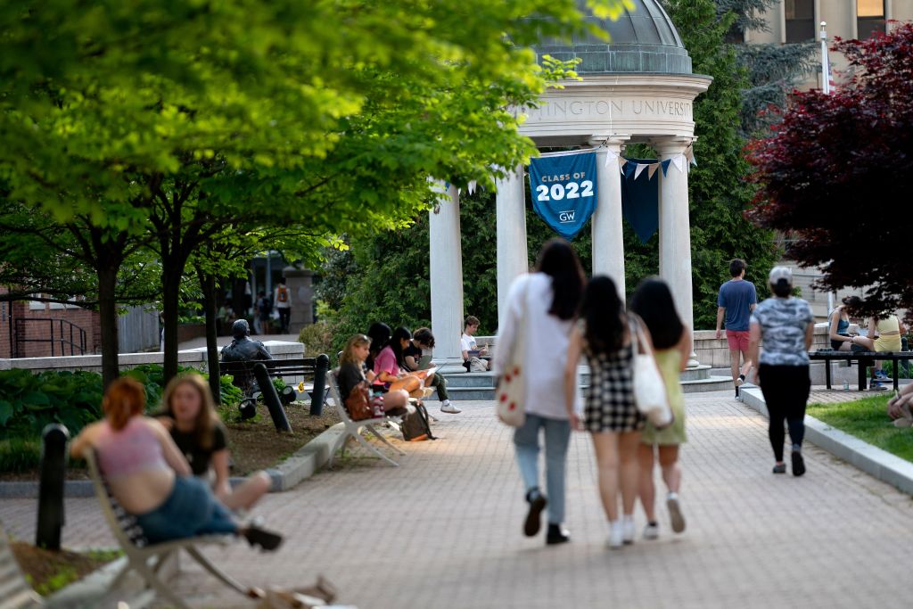 A Class of 2022 banner is displayed as students walk on campus at George Washington University in Washington, DC, as seen in May 2022. (Photo by Stefani Reynolds—AFP/Getty Images)