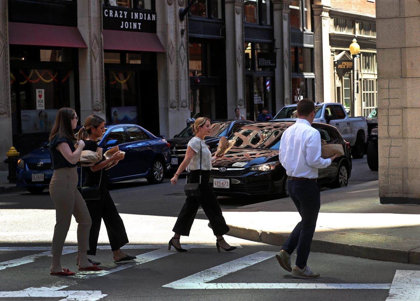 Office workers with take out for lunch in hand walk along Batterymarch Street Boston, as seen in August 2022. (Photo by David L. Ryan—The Boston Globe/Getty Images)