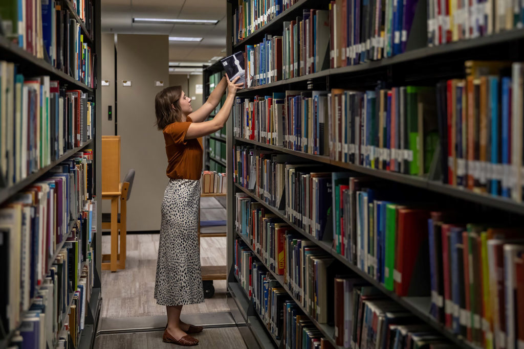 A work-study student restocks a bookshelf with books that students have returned at Baylor University in Waco, Texas, as seen in August 2022. (Photo by Xin Jin—Xinhua/Getty Images)