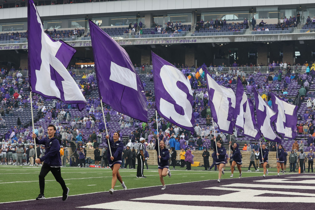 Cheerleaders run with flags spelling K-State during a college football game, as seen in September 2022 in Manhattan, KS. (Photo by Scott Winters—Icon Sportswire/Getty Images)