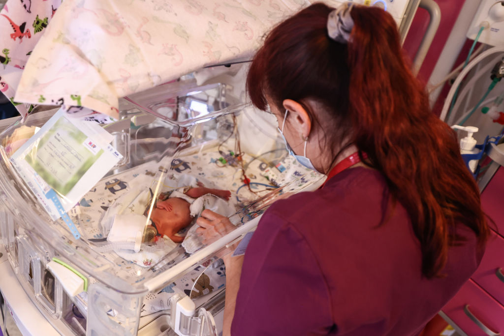 A nurse takes care of a quintuplet laying in an incubator in Krakow, Poland, as seen in February 2023. (Photo by Beata Zawrzel—NurPhoto/Getty Images)