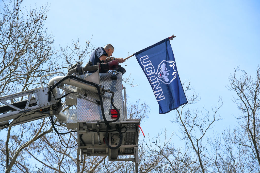 A fan holds a UConn Huskies flag during the UConn Championship Parade, as seen in April 2023, in Hartford, Connecticut. (Photo by Erica Denhoff—Icon Sportswire/Getty Images)