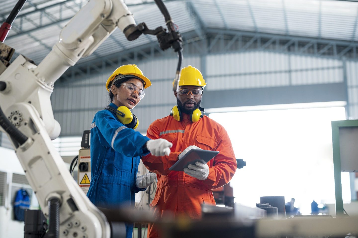 Female Quality Engineer and Male Production Engineer talking at welding robot in a factory.