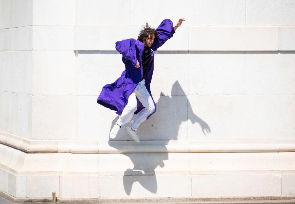 An NYU student wearing a graduation gown takes graduation photos in Washington Square Park, as seen in May 2021. (Photo by Noam Galai/Getty Images)