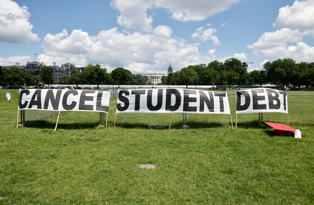 Advocates display a hand-painted sign on the Ellipse in front of The White House to call on President Joe Biden to sign an executive order to cancel student debt, as seen in June 2021. (Photo by Paul Morigi/Getty Images for We The 45 Million)
