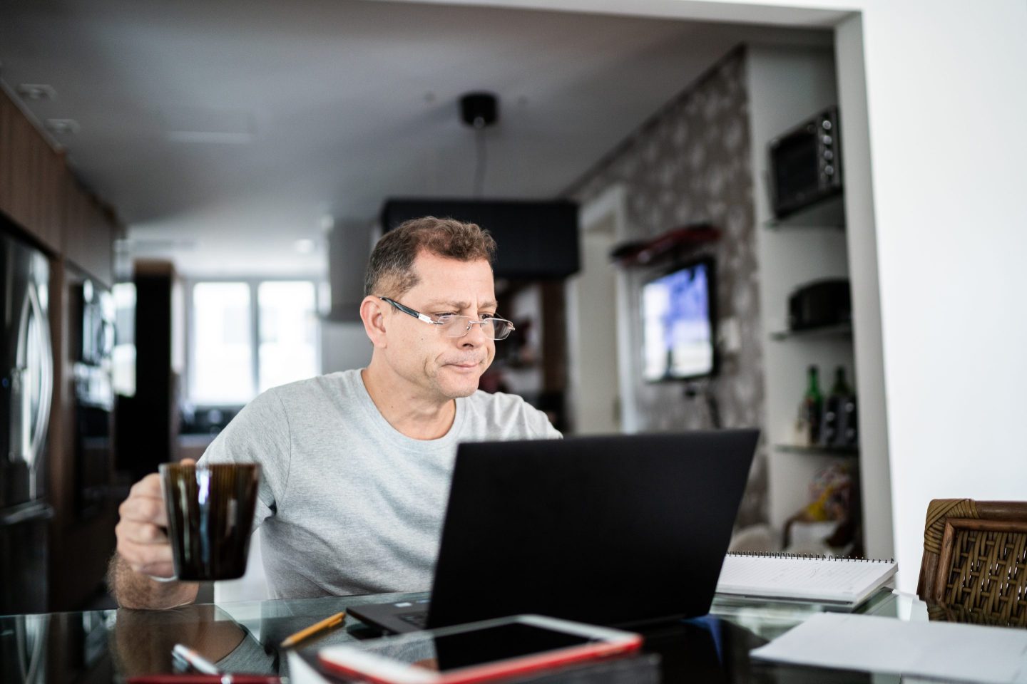 Photo of a man who is frowning while using a laptop at home