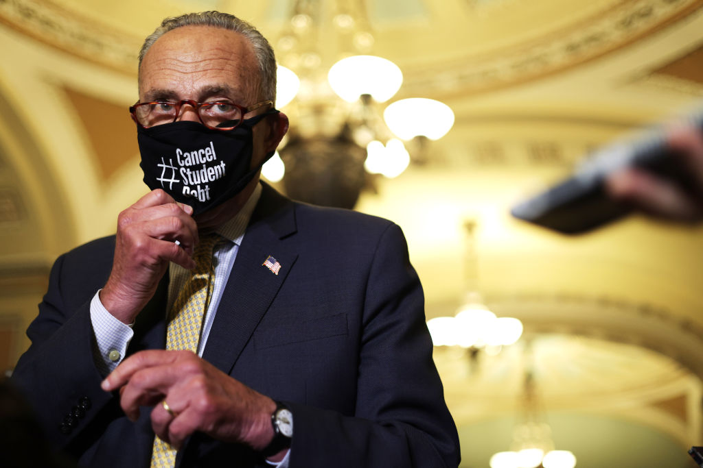 U.S. Senate Majority Leader Sen. Chuck Schumer (D-NY) puts on a mask that reads "Cancel Student Debt" during a news briefing after a weekly Senate Democratic Policy Luncheon at the U.S. Capitol, as seen in July 2021. (Photo by Alex Wong—Getty Images)