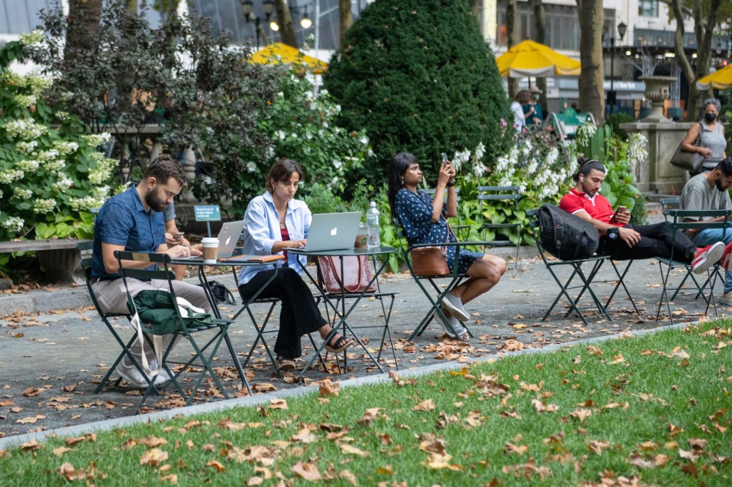 People sit on their laptops and phones in Bryant Park, as seen in August 2021 in New York City. (Photo by Alexi Rosenfeld/Getty Images)