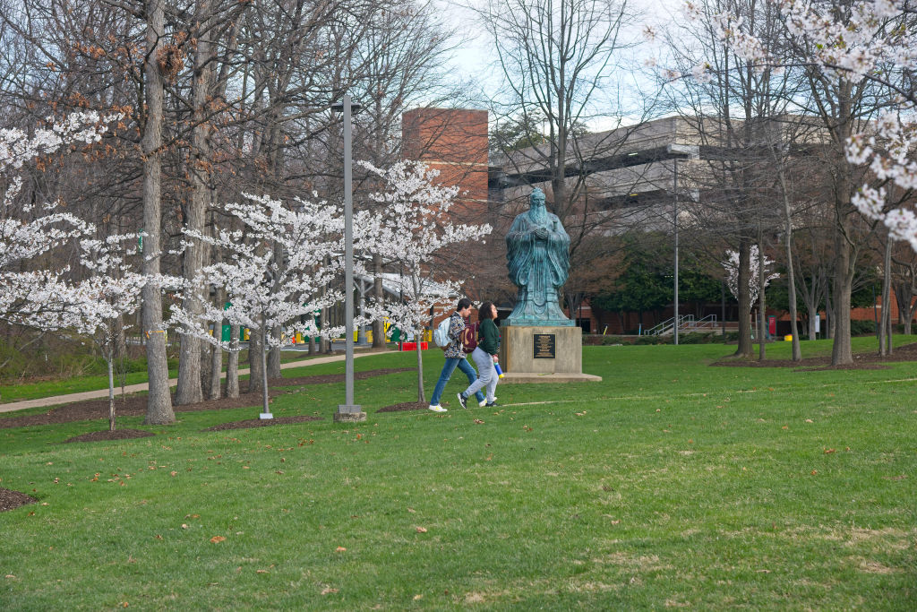 Statue of Confucius among cherry blossoms, George Mason University campus in Fairfax, Virginia, as seen in March 2022. (Photo by: Robert Knopes—UCG/Universal Images Group/Getty Images)