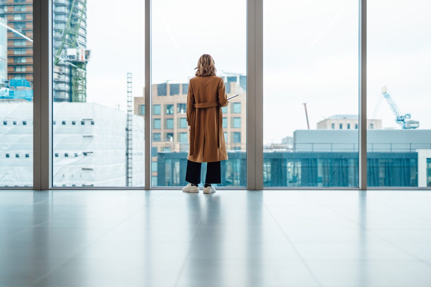 Woman looking out a window at buildings under construction