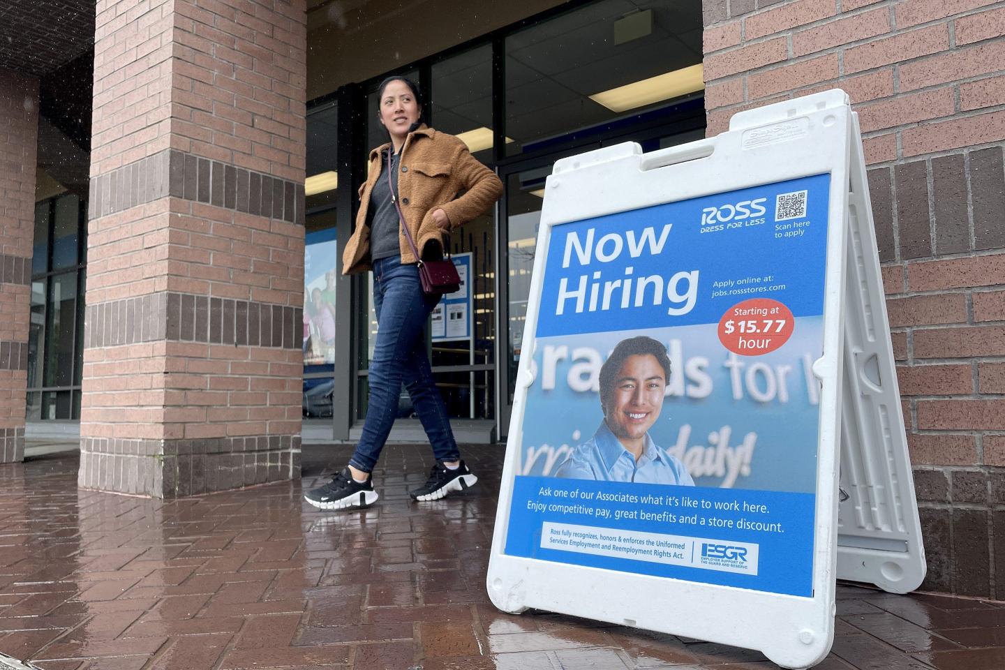 A customer walks by a now-hiring sign posted in front of a retail store in Novato, California