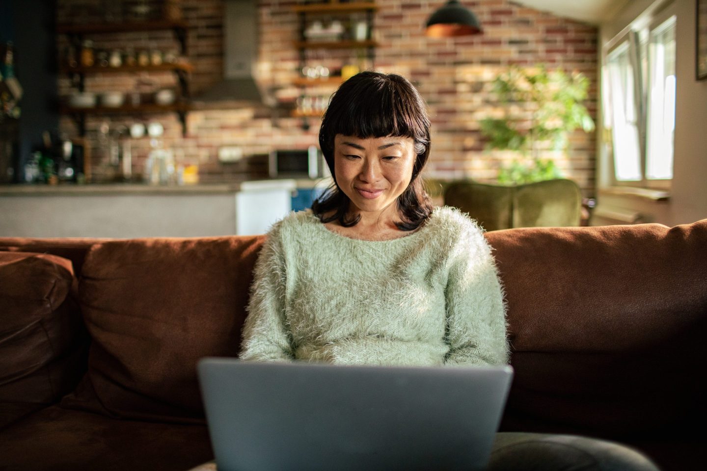 Young woman using a laptop on a couch in the living room
