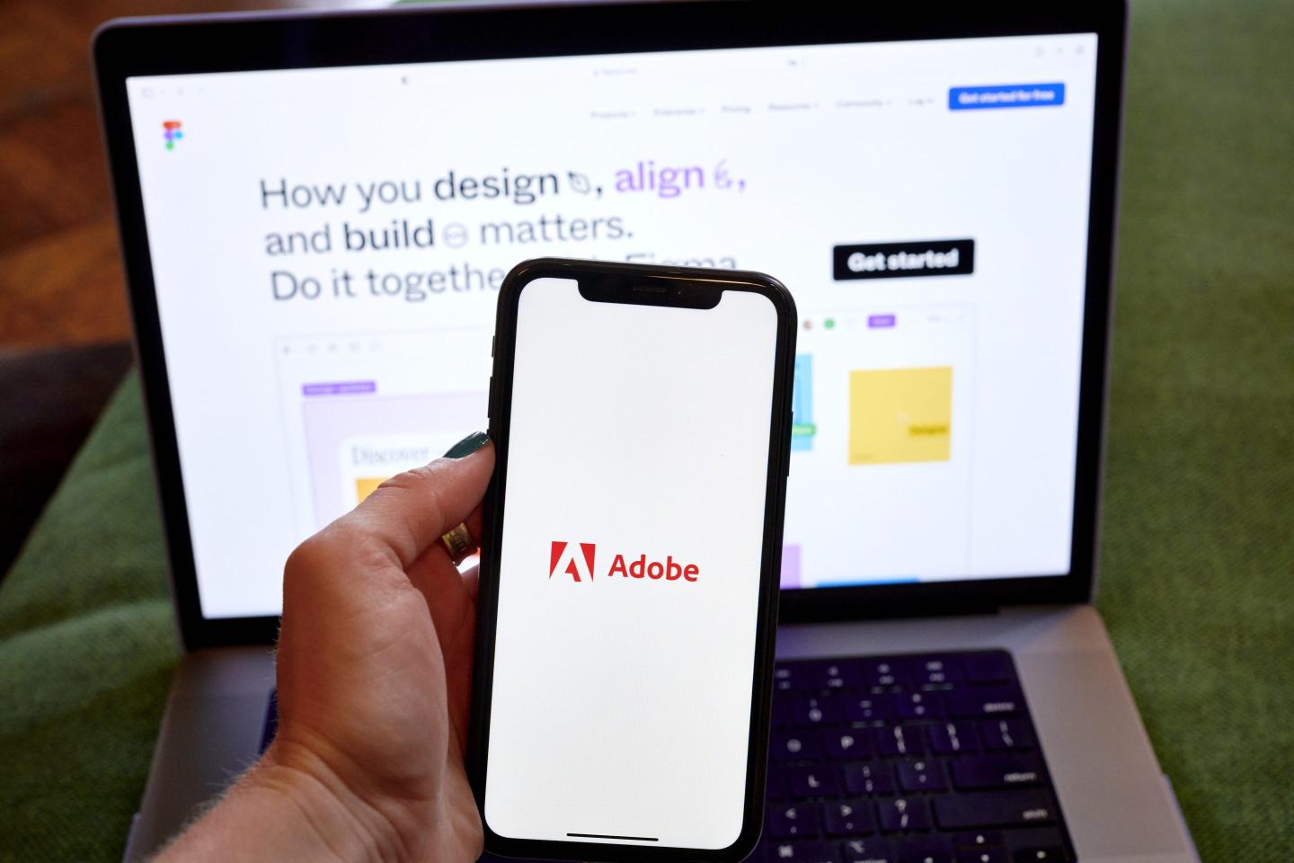 The Adobe logo on a smartphone and Figma website