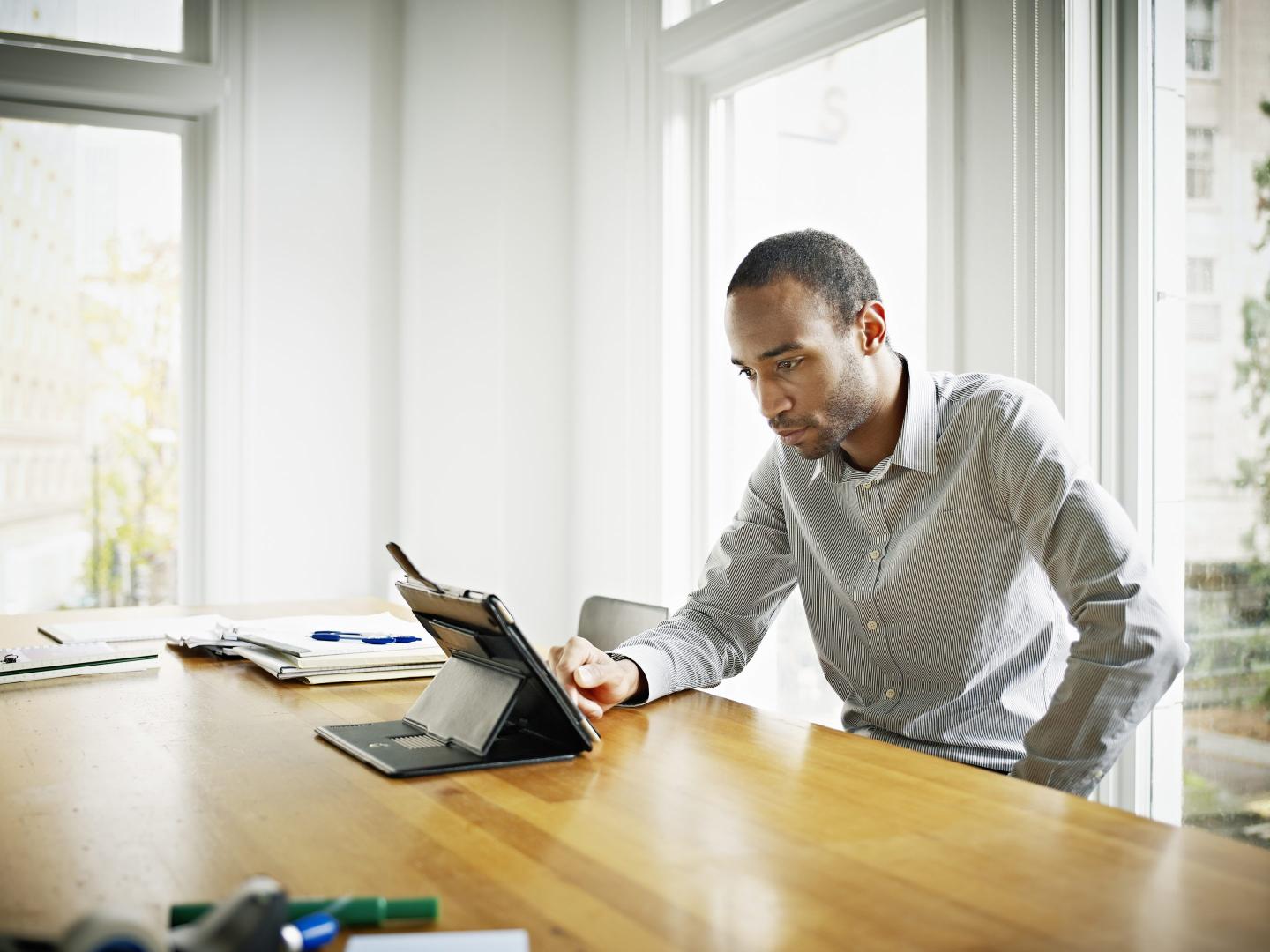Businessman sitting at office conference room table working on digital tablet