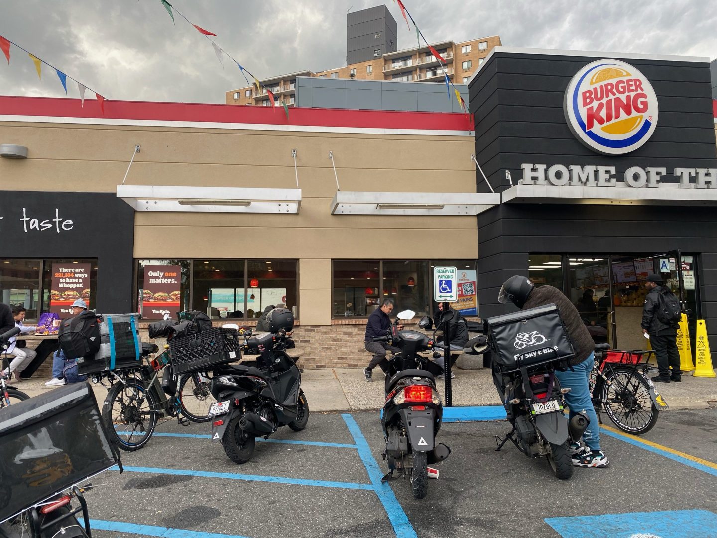 Group of delivery people waiting outside Burger King fast food restaurant, Queens, New York.