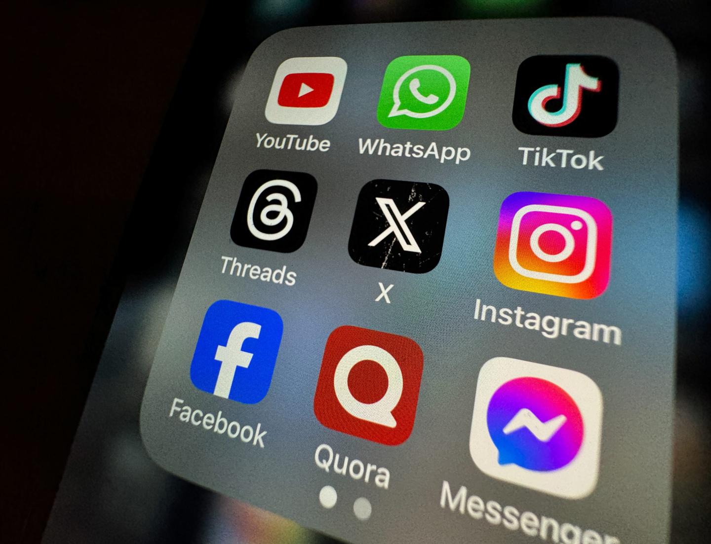 photo illustration the logo of US online social media and social networking site 'X' (formerly known as Twitter) is displayed centrally on a smartphone screen alongside that of Threads (L) and Instagram (R)