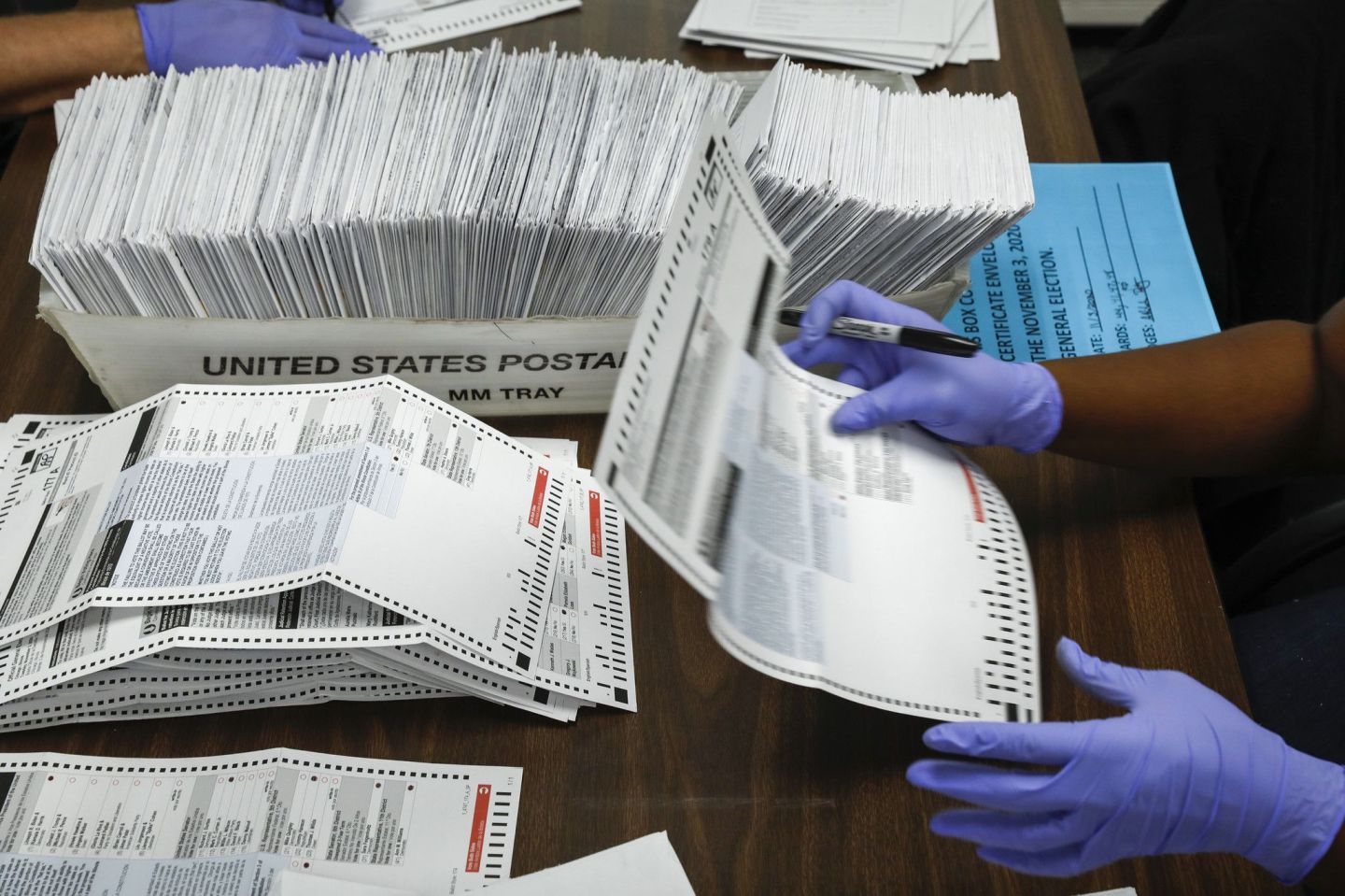 Election judges process mail-in ballots by opening envelopes