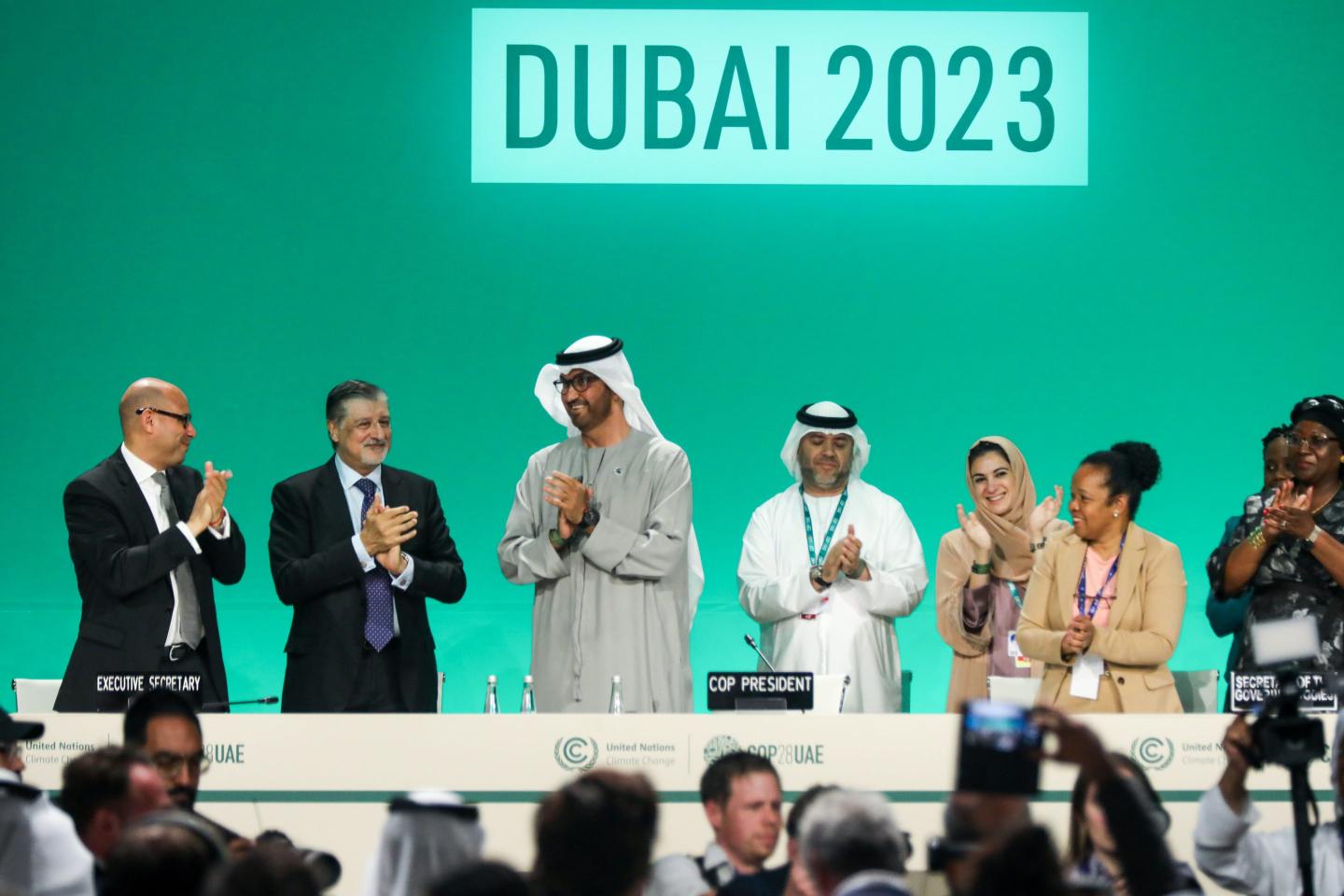 Delegates applaud after a speech by Sultan Ahmed Al Jaber (3L), President of the UNFCCC COP28 Climate Conference