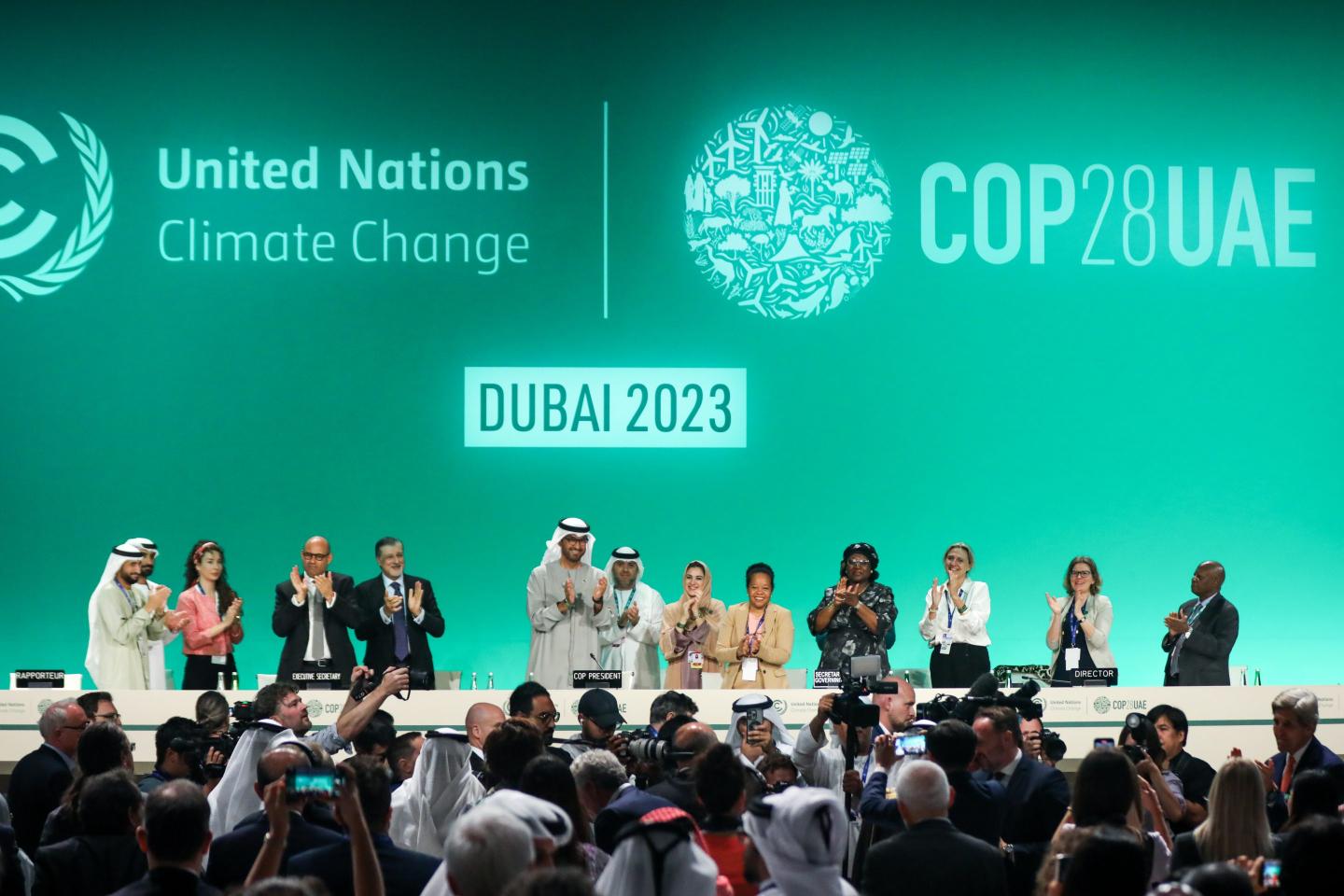 Delegates applaud after a speech by Sultan Ahmed Al Jaber (C), president of COP28, on day thirteen of COP28 on Dec. 13, 2023 in Dubai.