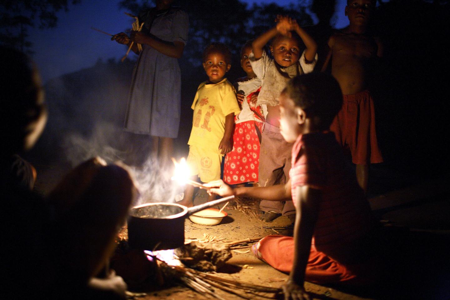 Young woman in Africa cooks over an open flame