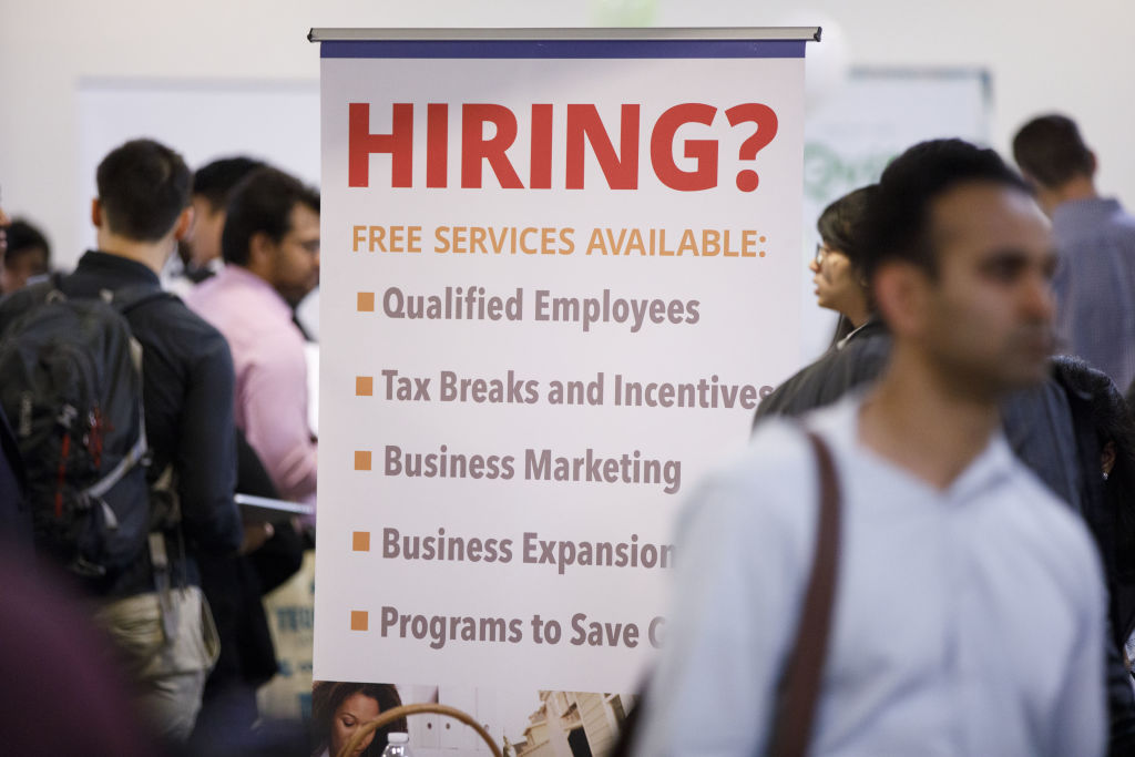 A "hiring" sign is displayed during the TechFair LA career fair in Los Angeles, California, as seen in March 2018. (Photographer: Patrick T. Fallon—Bloomberg/Getty Images)