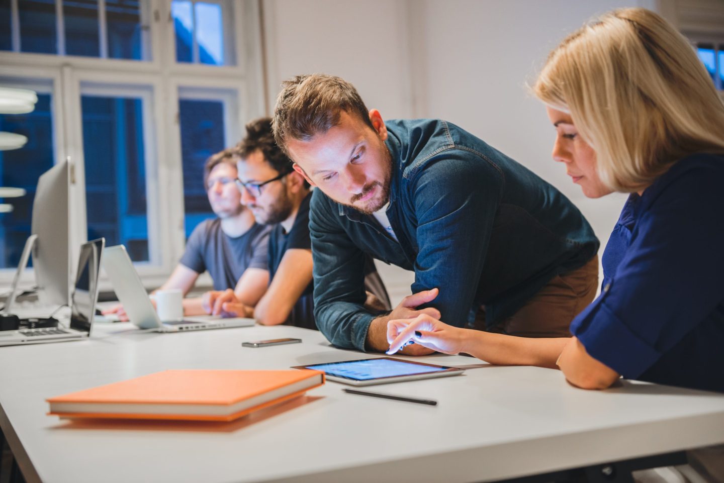 Man helps a woman with work on a tablet