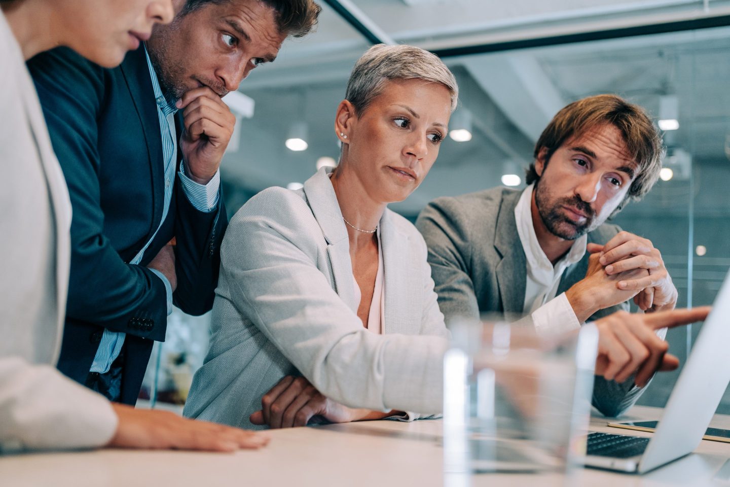 Four businesspeople work together on a laptop Business persons on meeting in the board room. Business team discussing new project on a meeting in a modern office.