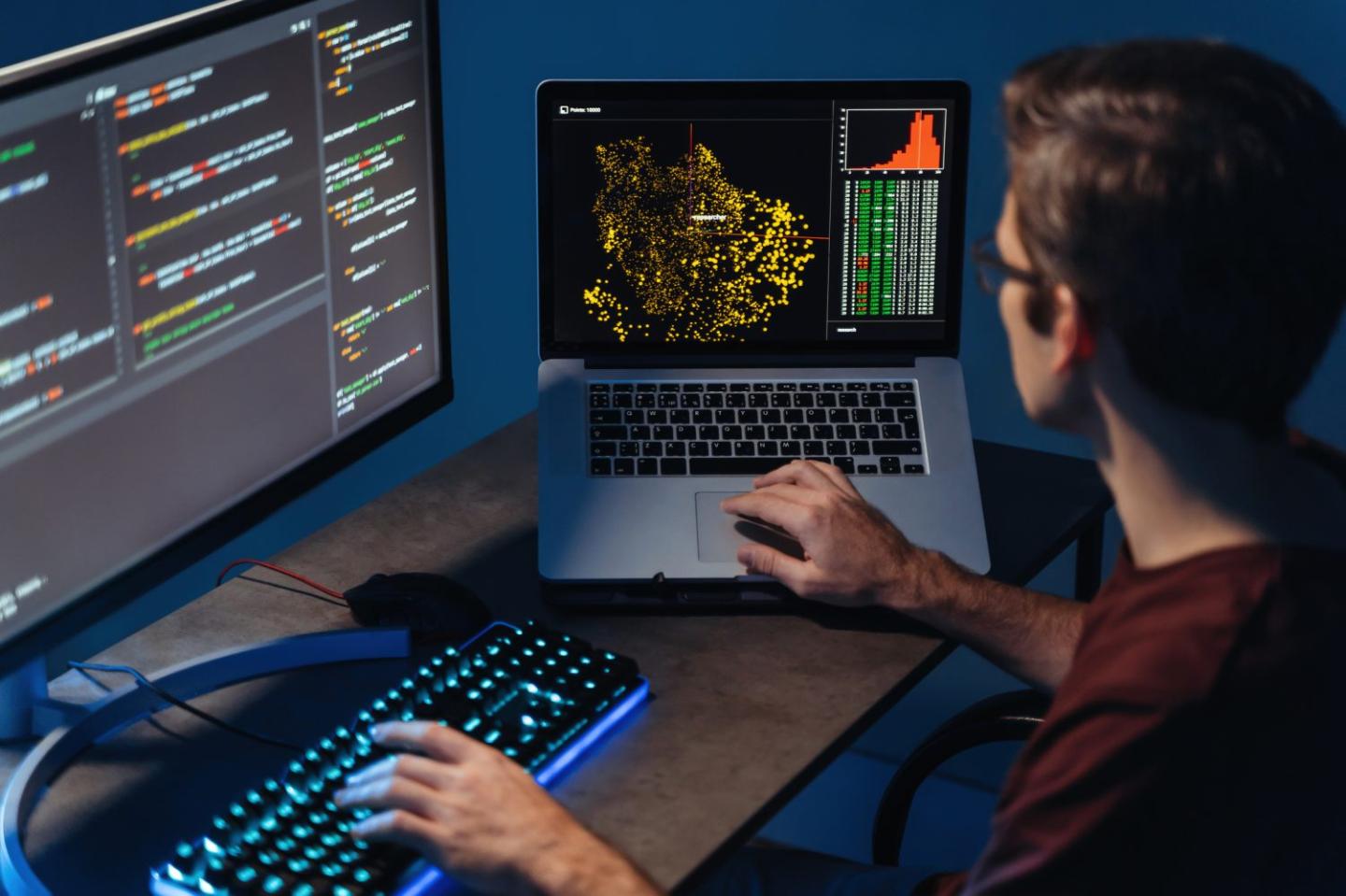 IT developer typing on pc and laptop with programming code on screen, using php language