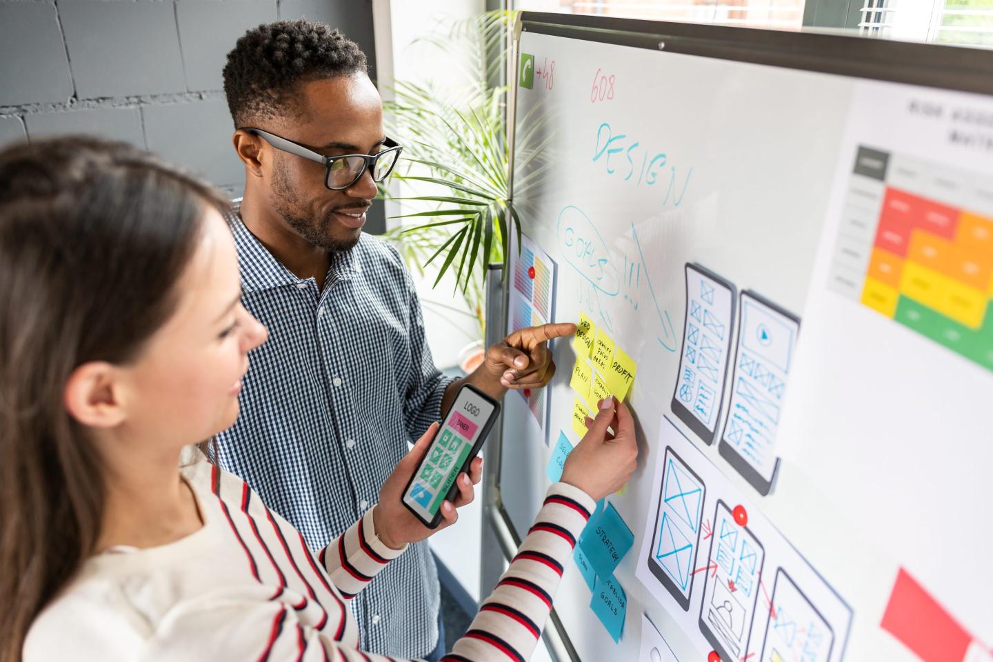 Two designers map out user experience on a white board