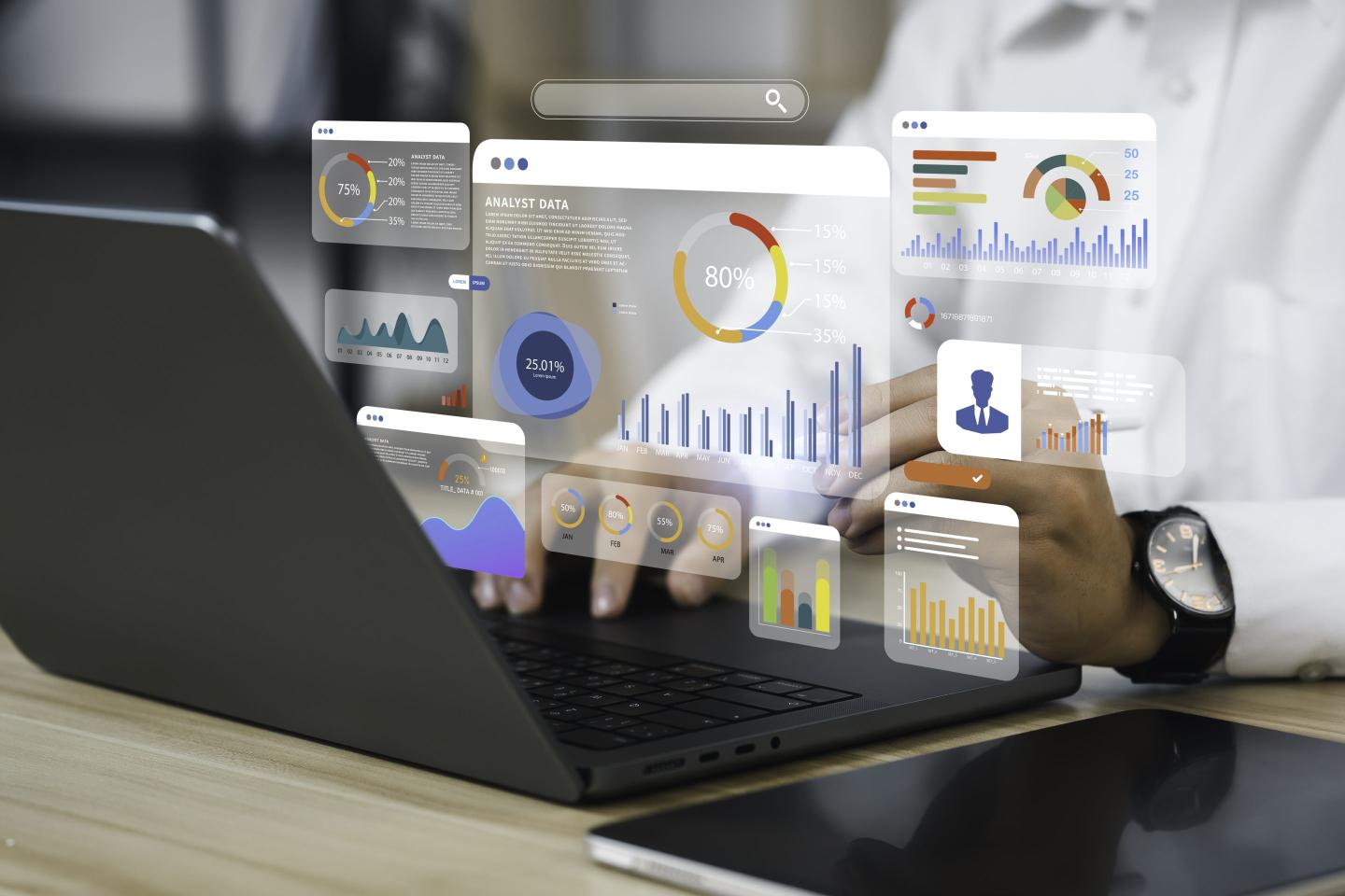 An analyst uses a laptop and data icons are popped out in front.