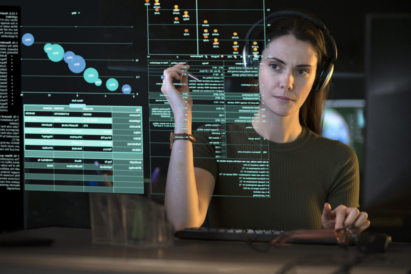 Women with headphones studies see-through data in front of her.