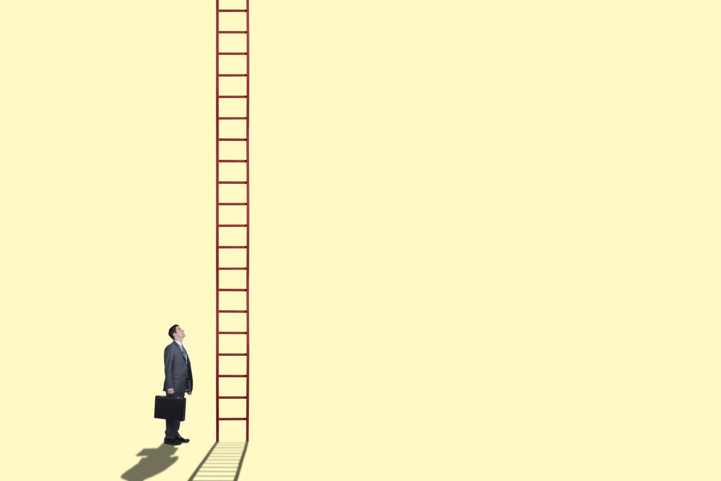 A businessman looks up at a tall ladder.