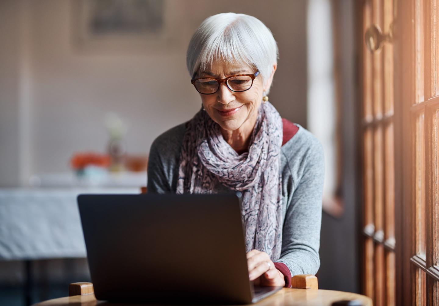 Woman with gray hair does research on her laptop