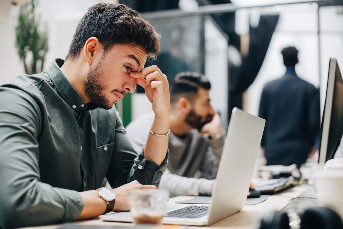 A man sits at his desk with his head in his hands.