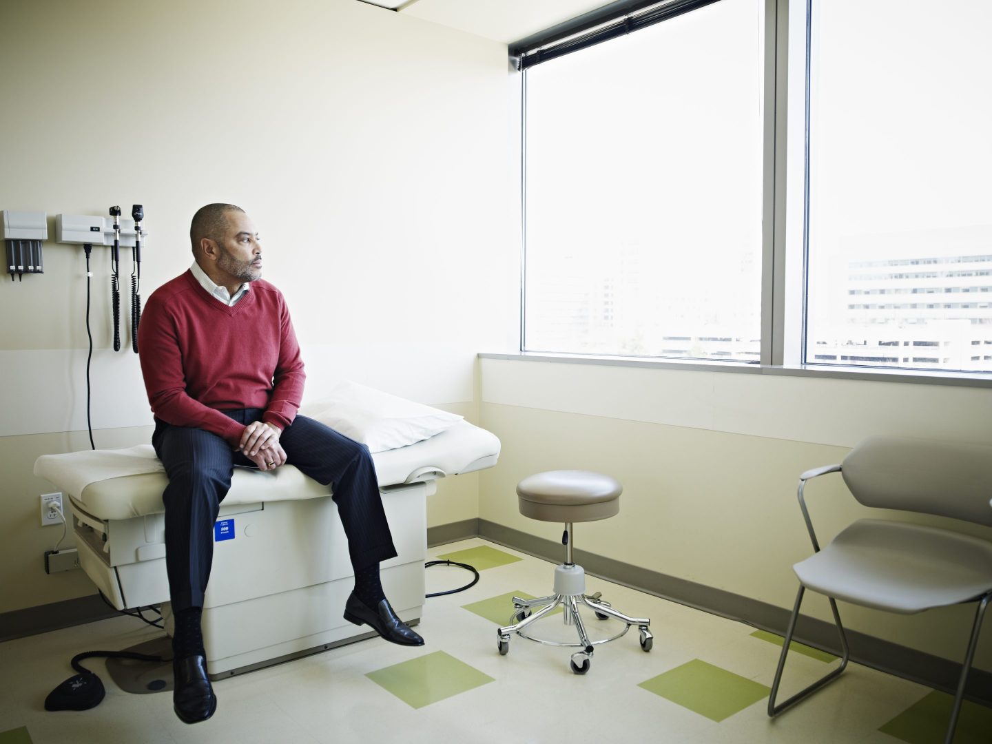 Male patient sitting on exam table in clinic room