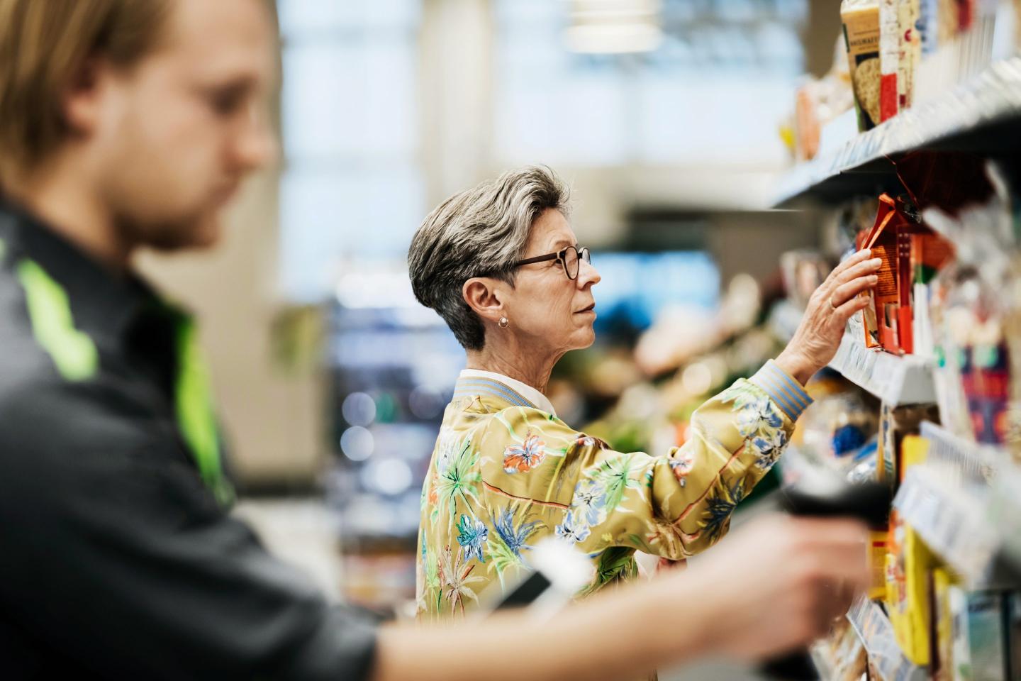woman picking some goods from the shelf while out shopping for groceries at her local supermarket.
