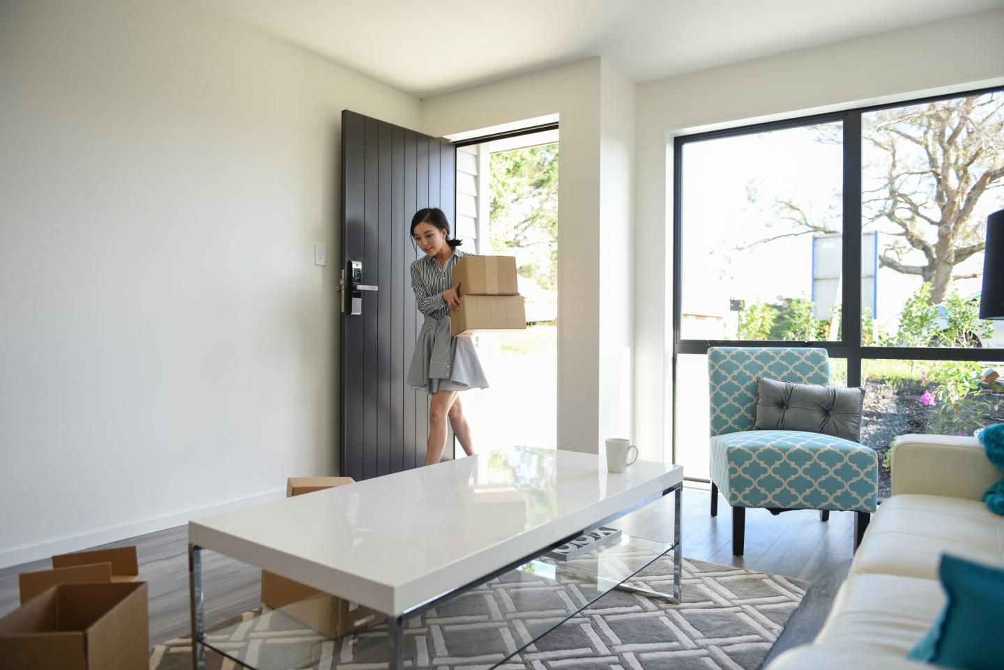 A young woman enters the door of a modern home