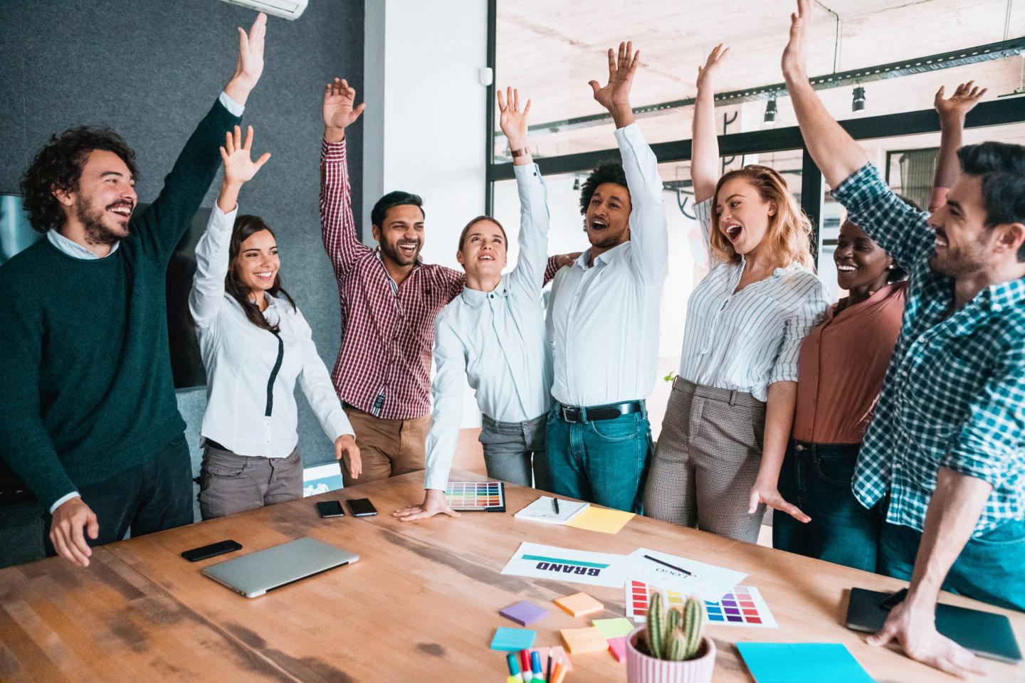 people standing around a table with their hands raised