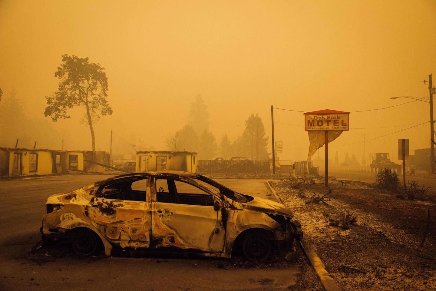 A charred vehicle is seen in the parking lot of the burned Oak Park Motel