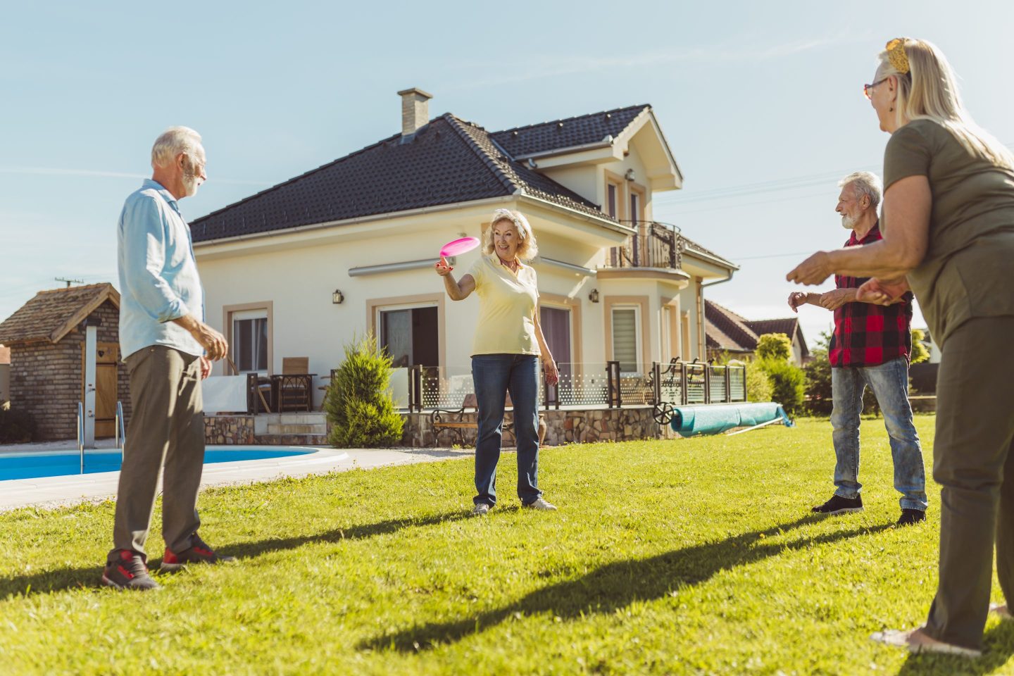 Group of boomers playing frisbee outside of their mansion.