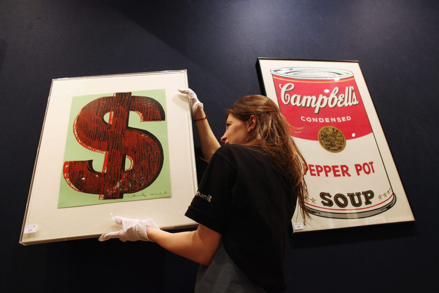 A gallery assistant adjusts a print of an Andy Warhol artwork in Bonhams auction house in 2011 in London.