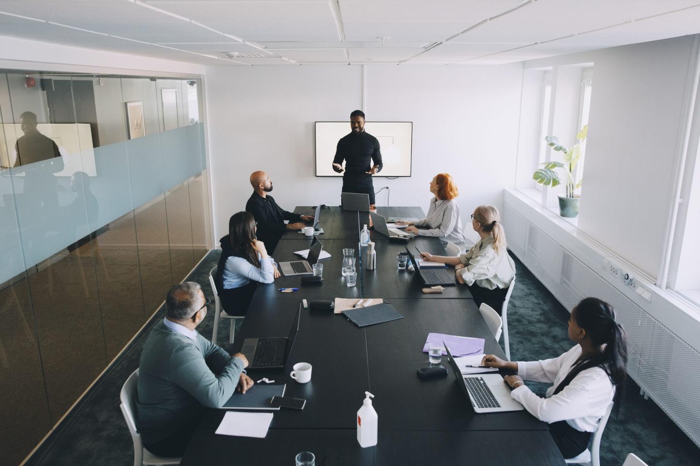 High angle view of businessman giving presentation colleagues in board room at office.